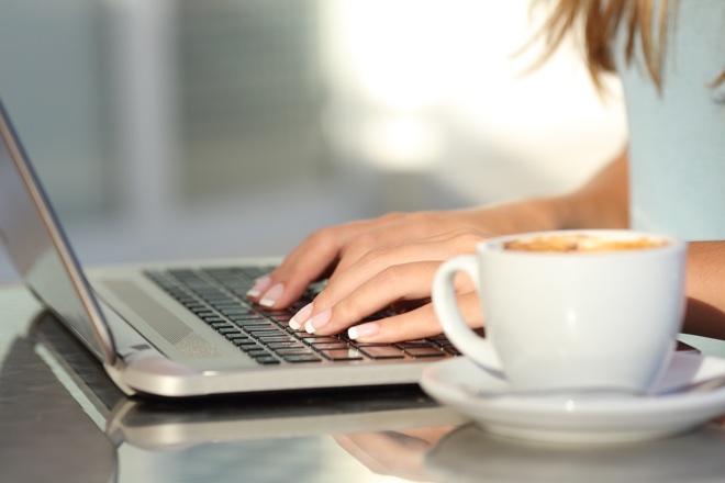 Close up of a woman hands typing in a laptop in a coffee shop terrace in the street 
