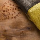What’s Going on With the Belgian Domain Market? Hot stamp imprint on a wooden surface - Made in Belgium. Belgium flag.