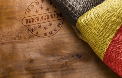 What’s Going on With the Belgian Domain Market? Hot stamp imprint on a wooden surface - Made in Belgium. Belgium flag.