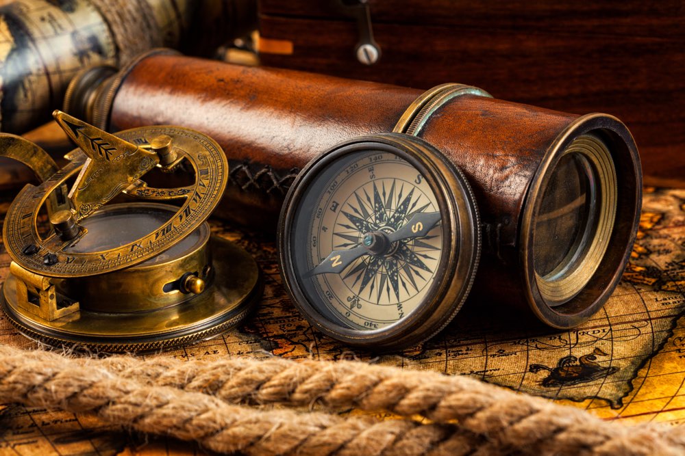Travel geography navigation concept background - old vintage retro compass with sundial, spyglass and rope on ancient world map