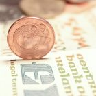 .IE Domain Names On a Roll As Business Confidence Grows Old Irish penny on edge on top of an old Irish pound note (punt) with blurred Irish coins in background