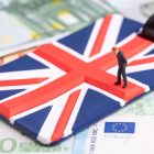 Brexit and .EU Domains Europe, Brexit or Britain economy or financial concept, miniature figure businessman country leader standing on Union Jack UK national flag on pile of Euro banknotes money.