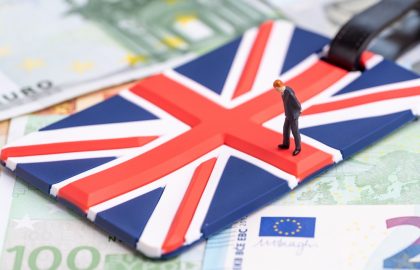 Brexit and .EU Domains Europe, Brexit or Britain economy or financial concept, miniature figure businessman country leader standing on Union Jack UK national flag on pile of Euro banknotes money.