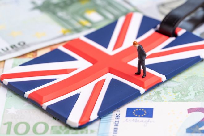 Europe, Brexit or Britain economy or financial concept, miniature figure businessman country leader standing on Union Jack UK national flag on pile of Euro banknotes money.