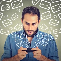 Important: IOL, EsatClear & OceanFree Email Closeup portrait young shocked man busy sending messages emails from smart phone email icons flying of mobile phone isolated on gray wall background. Telecommunications, internet, data plan concept